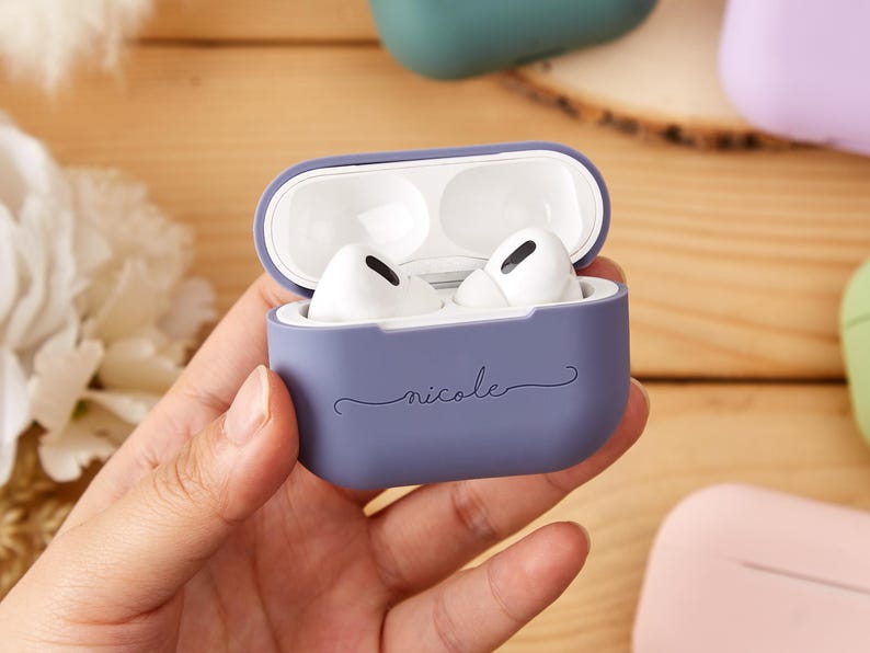 May include: A purple silicone case for AirPods with the name "nicole" written on it in a cursive font.