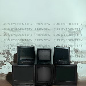 May include: A collection of six black CRT televisions stacked against a distressed white wall. The TVs vary in size and design, with visible screens and control panels. The text "JUS EYEDENTIFY PREVIEW" is faintly visible on the wall.