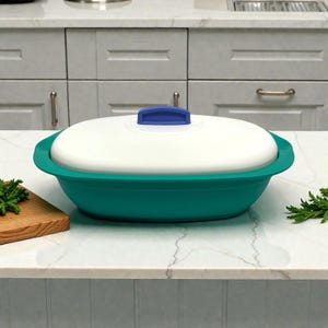 Puede incluir: Contenedor ovalado para almacenamiento de alimentos en color turquesa y blanco, con asa azul en la tapa. El contenedor está sobre una encimera blanca en una cocina. Diseñado para el almacenamiento de alimentos.