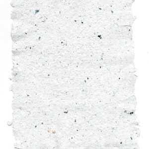 May include: A sheet of white handmade paper with a rough texture and flecks of color throughout.
