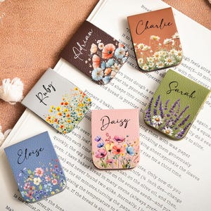 May include: A collection of floral-themed bookmarks, each with a name: Adrian, Charlie, Daisy, Eloise, Ruby, and Sarah. The bookmarks feature colorful flower designs and are arranged on an open book.