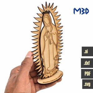 Puede incluir: Corte de madera de la Virgen María, Nuestra Señora de Guadalupe, con una corona y un halo. El corte está sobre una base de madera con el texto "Nuestra Señora de Guadalupe" inscrito en él.