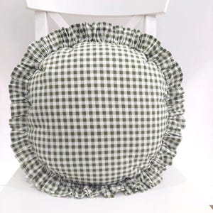 Könnte beinhalten: Ein rundes grünes und weißes Gingham-Kissen mit einem Rüschenrand.