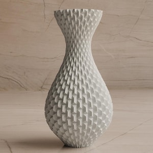 May include: A white decorative vase with a textured, geometric pattern. The vase has a wide base that tapers to a narrow neck and flared opening. The vase is approximately 12 inches tall and is made of a solid material.