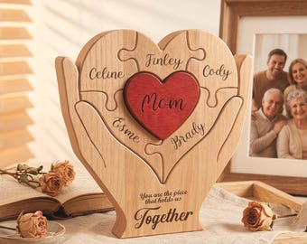May include: Wooden heart-shaped puzzle with a red heart in the centre, engraved with the word "Mom." The puzzle pieces are engraved with names. The base reads "You are the piece that holds us Together."
