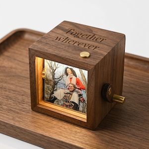 May include: A wooden music box with a photo display. The box is engraved with the words "Together wherever". The photo shows two people. The box has a gold-coloured knob and button.