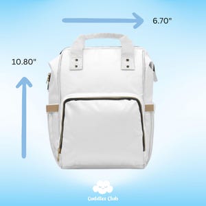 May include: White diaper bag backpack with gold accents and a black zipper. The bag measures 10.80 inches tall and 6.70 inches wide. Cuddles Club logo is at the bottom of the image.