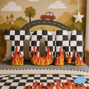 May include: A decorative bed set featuring the name "TOM" in large, checkered letters with flames. The letters are black and white checkered with a flame design in red, orange, and yellow. The background includes a road, car, and clouds.