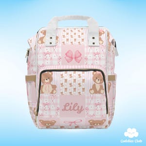 May include: Pink and white diaper bag with a patchwork design featuring teddy bears, bows, and the name "Lily".
