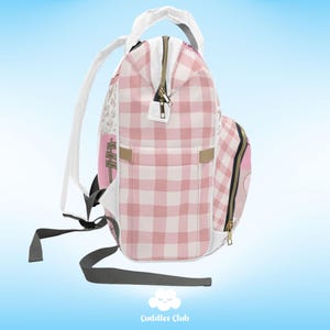 May include: A pink and white checkered backpack with a white zipper and a gold zipper pull. The backpack has a large pocket on the front and a smaller pocket on the side. The backpack is made of a soft, durable material and is perfect for carrying books, clothes, and other essentials.