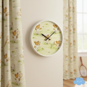 May include: A round white wall clock featuring a tennis-themed design with cartoon teddy bears playing tennis on a green background. The clock is mounted on a cream-colored wall, with matching curtains on either side.