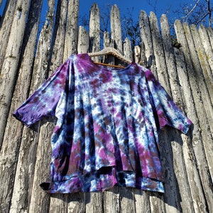 May include: A purple and blue tie-dye shirt with a loose fit and a slightly longer back hem.