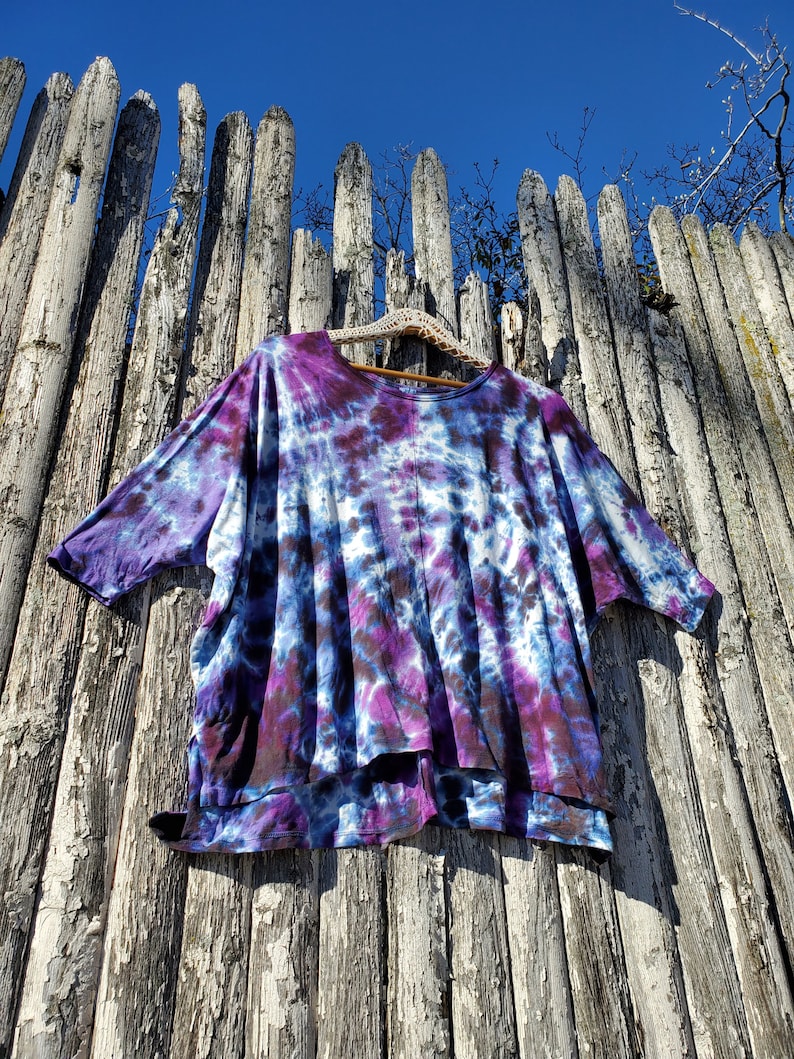 May include: A purple and blue tie-dye shirt with a loose fit and a slightly longer back hem.