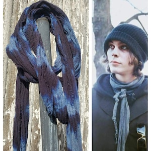May include: A blue and black tie-dye scarf is wrapped around a metal pole. The scarf is made of a soft, textured fabric.