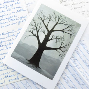 May include: A watercolour painting of a bare tree with a dark grey trunk and branches against a light blue and grey background. The tree is silhouetted against the sky, and the background is a soft, muted blue.
