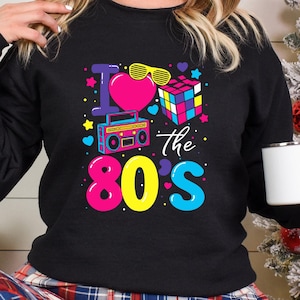 a woman wearing a black sweatshirt with the words i love the 80's on