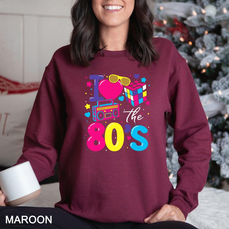 a woman wearing a maroon sweatshirt with the words the 80's printed on it