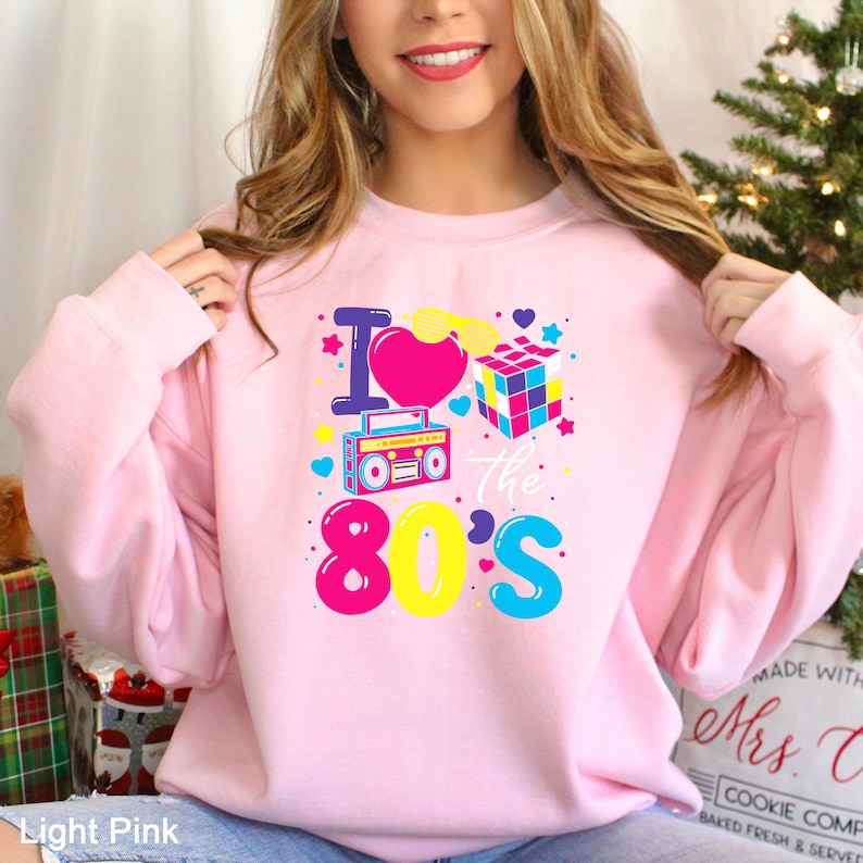 a woman wearing a pink sweatshirt that says i love the 80's