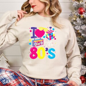 a woman wearing a sweatshirt that says i love the 80's