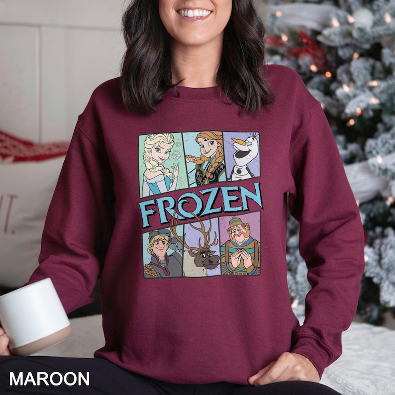 Puede incluir: Sudadera granate con un gr&aacute;fico colorido de personajes de la pel&iacute;cula "Frozen". El dise&ntilde;o incluye a Elsa, Anna, Olaf, Kristoff, Sven y un personaje con un sombrero verde. La palabra "FROZEN" est&aacute; impresa en letras azules.