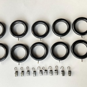 May include: Ten black curtain rings with silver hooks and twelve silver curtain clips.