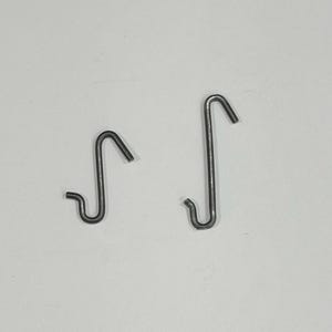 May include: Two grey metal S-hooks of different sizes, each featuring a curved design with a small hook at the bottom and a larger hook at the top. The hooks are made of a smooth, rounded wire material and have a consistent matte grey finish.