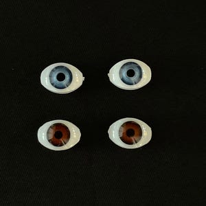 May include: Four doll eyes, two blue and two brown, on a black background.