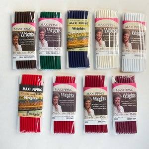 May include: Assortment of 10 spools of maxi piping trim in various colors, including red, green, brown, white, and navy blue. Each spool is labeled "Wrights Maxi Piping" and includes the color name and yardage.