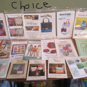 May include: A collection of sewing patterns, including patterns for aprons, bags, placemats, and potholders. The patterns are in plastic sleeves and feature colorful illustrations and text. The word "Choice" is written at the top.
