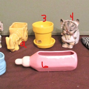 May include: A collection of vintage ceramic planters in various shapes and colors. Includes a kitten, a yellow wagon, a yellow pot, a baby bottle, a blue boot, and a black and white duck planter.