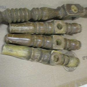 May include: Four wooden chair legs with a turned design. The legs are brown and have a worn finish.