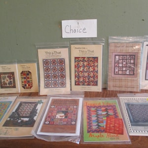 May include: A collection of 10 quilt patterns featuring various designs, including "This & That" and "Lapped Edges". The patterns are printed on white paper with colorful illustrations and text. The word "Choice" is written on a white card.