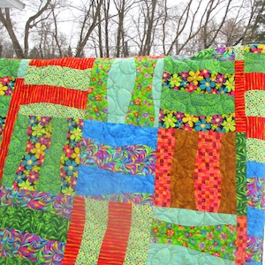 May include: A colorful patchwork quilt with a variety of floral and geometric patterns in shades of green, red, blue, and yellow.