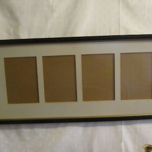 May include: A rectangular black picture frame with four openings. The frame has a gold inner border and a cream-colored mat. The openings are rectangular and have a brown backing.