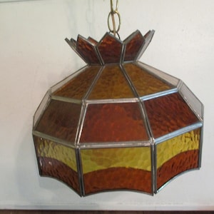 May include: A stained glass ceiling light fixture with a geometric design in shades of brown and yellow.