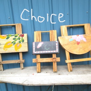 May include: Three small wooden easels with painted designs. One has lemons, another a chalkboard, and the third a pink flower. The word "Choice" is written above them in white.