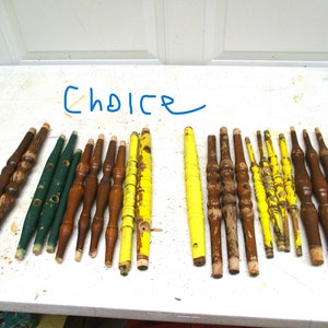 May include: A collection of wooden spindles in various colors and styles. Some are painted green, yellow, and brown, while others are natural wood. The word "Choice" is written in blue marker.