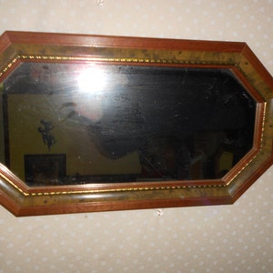May include: Octagonal mirror with a wooden frame and gold trim. The mirror has a beveled edge and is surrounded by a decorative border.