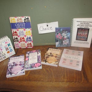 May include: A collection of quilting books and patterns, including "365 Quilt Blocks a Year", "The Quilt of Life", "When I'm on My Knees", "The Quilt of Life", "Row by Row Patterns and Recipes", and "Quilting".