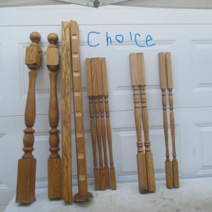 May include: A collection of wooden balusters and newel posts in various styles. The pieces are made of light brown wood and are arranged against a white background. The word "Choice" is written in blue marker.