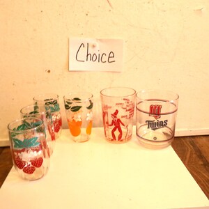 May include: A collection of vintage drinking glasses with various fruit and graphic designs. One glass features a red and white Twins logo. A handwritten note above the glasses reads "Choice".