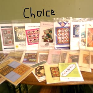 May include: A collection of quilting patterns, displayed on a wooden surface. The patterns feature various designs, including geometric shapes and floral motifs. The word "Choice" is written above the patterns.