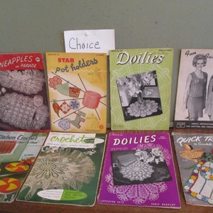 May include: A collection of vintage crochet pattern books, featuring titles like "Pineapples on Parade," "Star Pot Holders," and "Doilies." The covers display colorful illustrations and text, showcasing various crochet projects. The books are arranged on a wooden surface.
