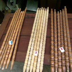 May include: Three sets of four long, slender wooden spindles arranged in rows. The first set is light brown, the second is pale unfinished wood, and the third is dark brown. Each spindle features a repeating turned bead design. The word Choice is written vertically in white text on the right side, with numbered tags 1, 2, and 3 placed on each set.