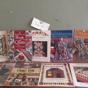 May include: A collection of ten quilt pattern books with various titles, including "Christmas Greetings", "The Thimbleberries Book of Quilts", "Summer House Traditions", "A Thimbleberries Housewarming", "Fireside Flannel Quilts", "Splished Quilts", "Cider Hill Flannel Quilts", "Farmhouse Flannels", "Big Block Christmas Quilts", and "Thimbleberries Christmas Quilts".
