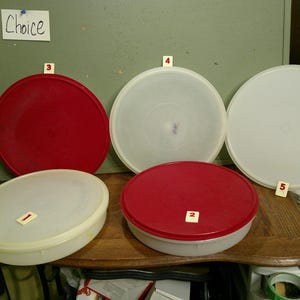 May include: Five round plastic storage containers and lids, arranged in two rows. Two containers are red, and three are translucent white. Each item is labeled with a small white square numbered one through five. A sign labeled Choice is visible.