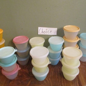 May include: A collection of 15 small plastic storage containers in various colors, including yellow, blue, pink, and white. The containers are stacked in groups of three or four. The word "Choice" is written on a white card in the background.
