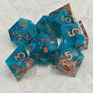 May include: Set of teal blue and copper dice with gold flecks. The dice are numbered 1-20.