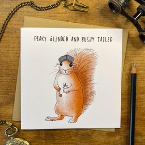 May include: A greeting card featuring a cartoon illustration of a squirrel wearing a flat cap and holding a small bottle. The text on the card reads "Peaky Blinded and Bushy Tailed."