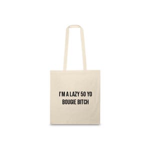 Peut inclure: Sac fourre-tout crème avec le texte noir "I'M A LAZY 50 YO BOUIGIE BITCH". Le sac a deux longues poignées et est fait d'un tissu de couleur claire.